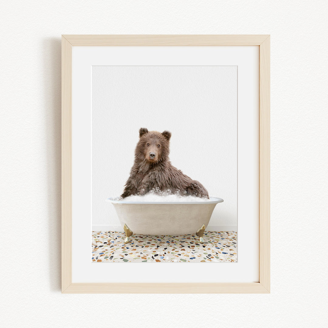 A brown bear sitting in a white bathtub filled with water, with a tiled floor in the background.
