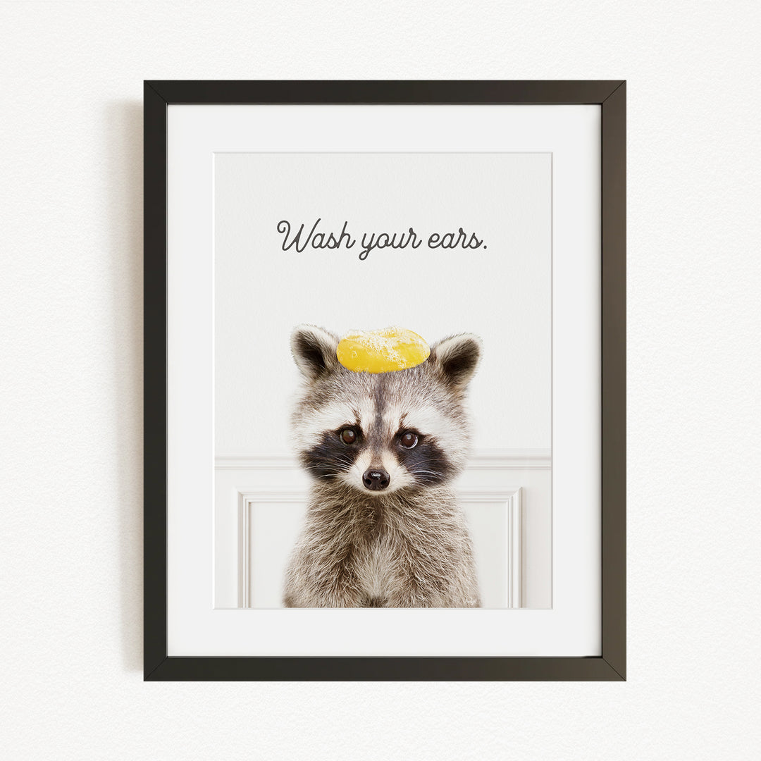 A raccoon wearing a yellow hat with the text "Wash your ears" written on it.