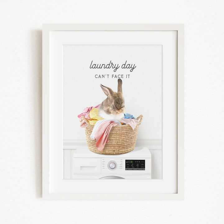 A cute rabbit sitting in a basket filled with laundry, with the text "laundry day can't face it" displayed above the image.