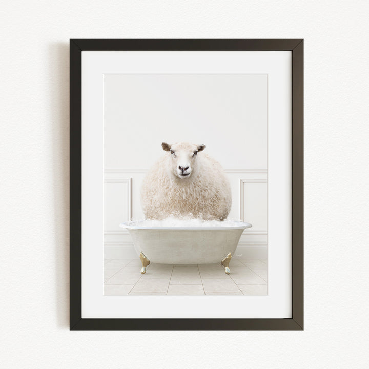 A fluffy white sheep sits in a white bathtub filled with bubbles, looking directly at the camera.