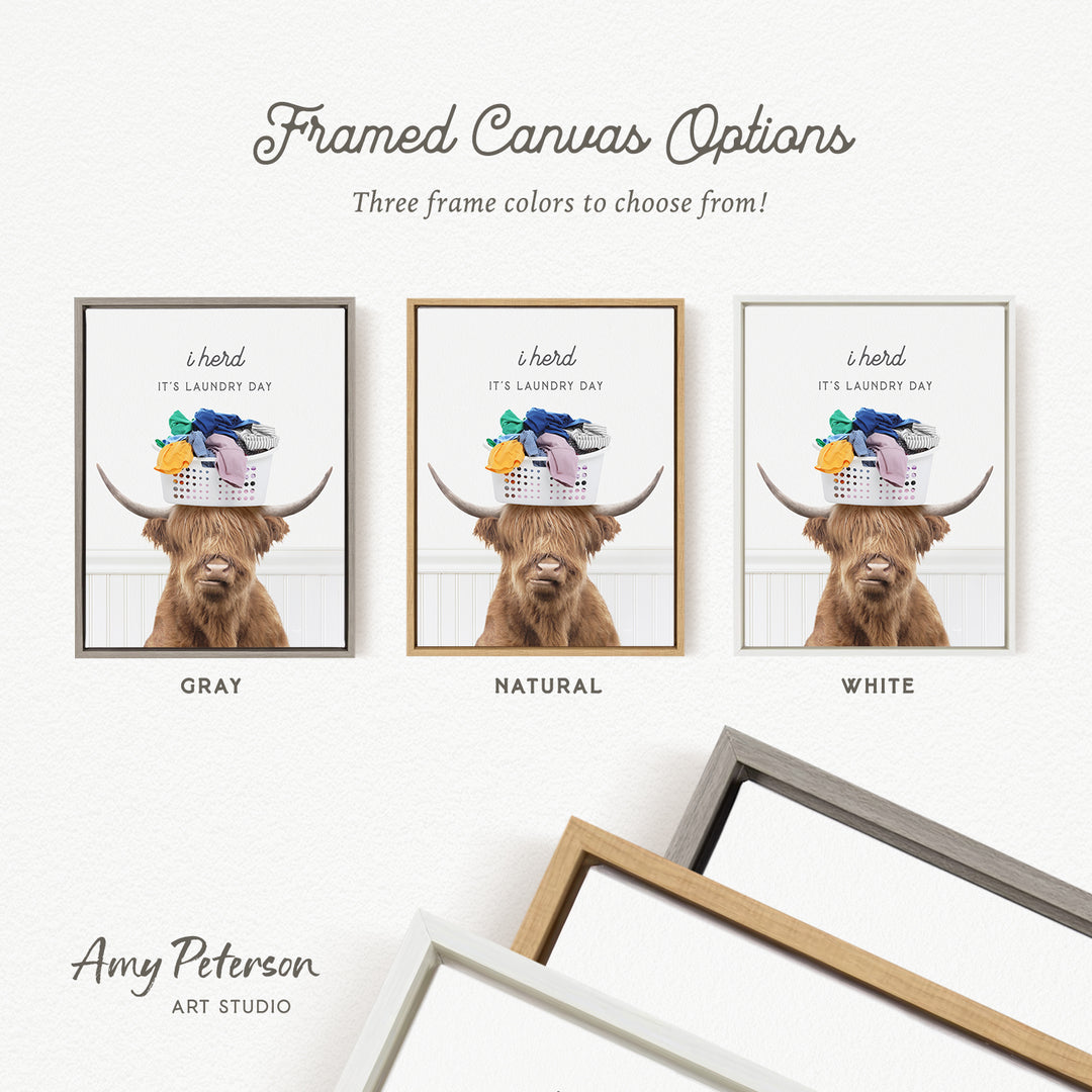 The image is a framed canvas option featuring a brown Highland cow with a basket of laundry on its head, accompanied by text indicating three frame colors to choose from: gray, natural, and white.