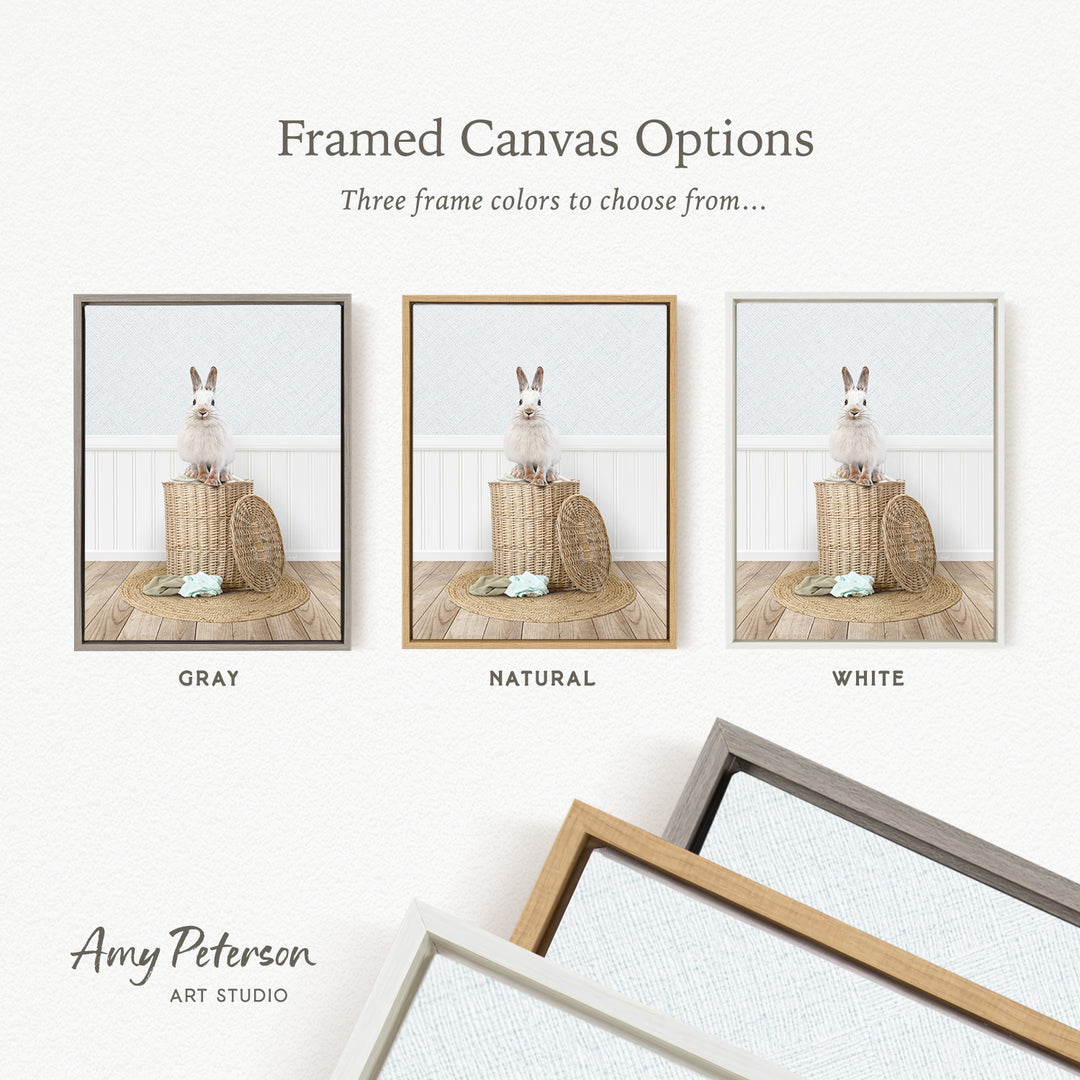 The image is a framed canvas option showcasing three different frame colors: gray, natural, and white. The canvas features a white rabbit sitting on a wooden surface, with a basket nearby.