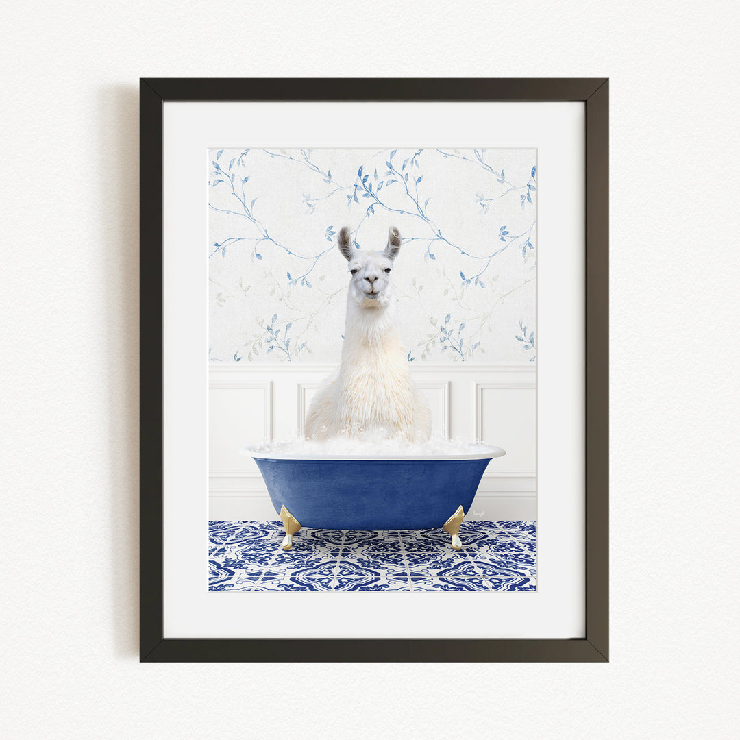 A white llama sitting in a blue bathtub filled with bubbles, against a white wall with a blue floral pattern.