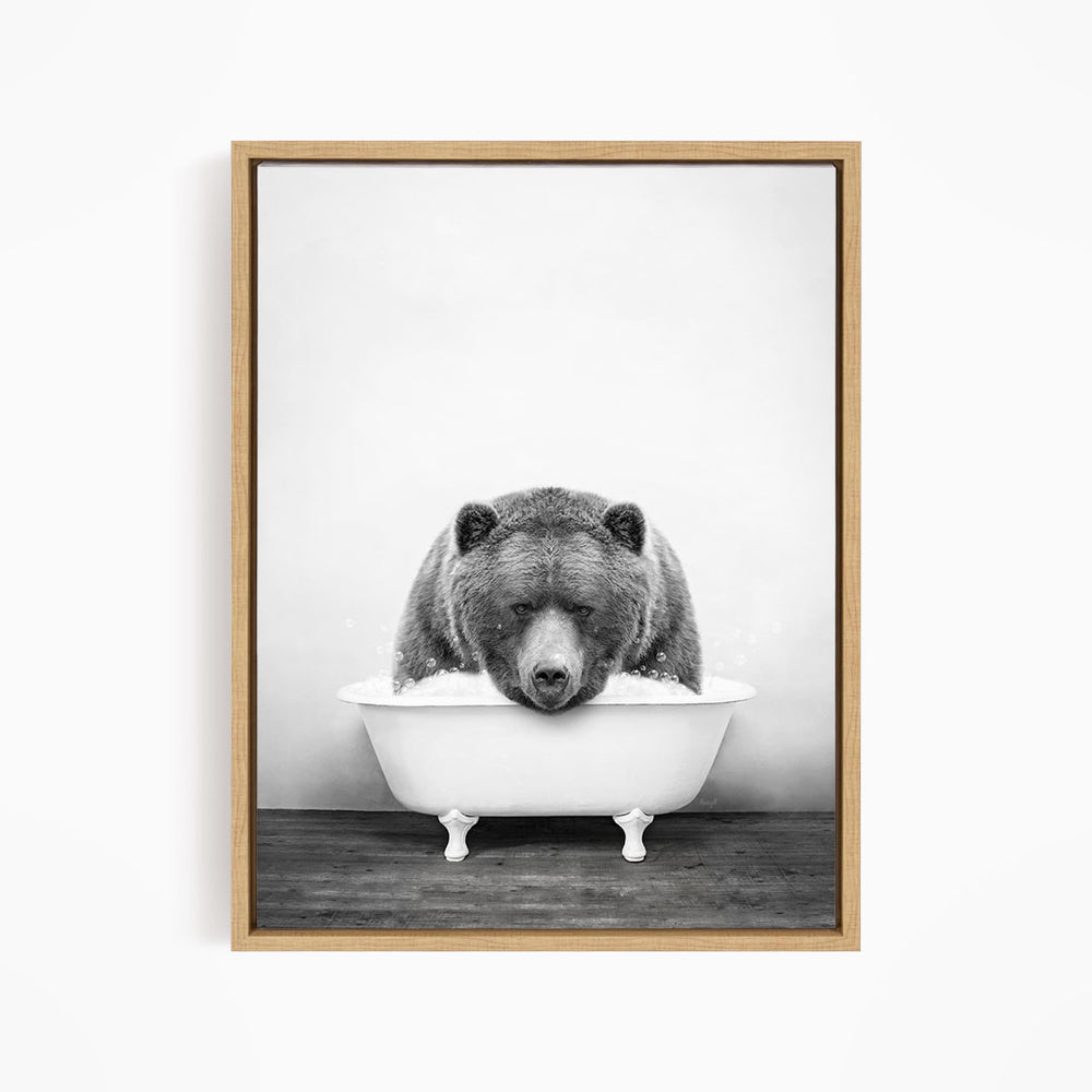 A black and white image of a bear sitting in a bathtub.