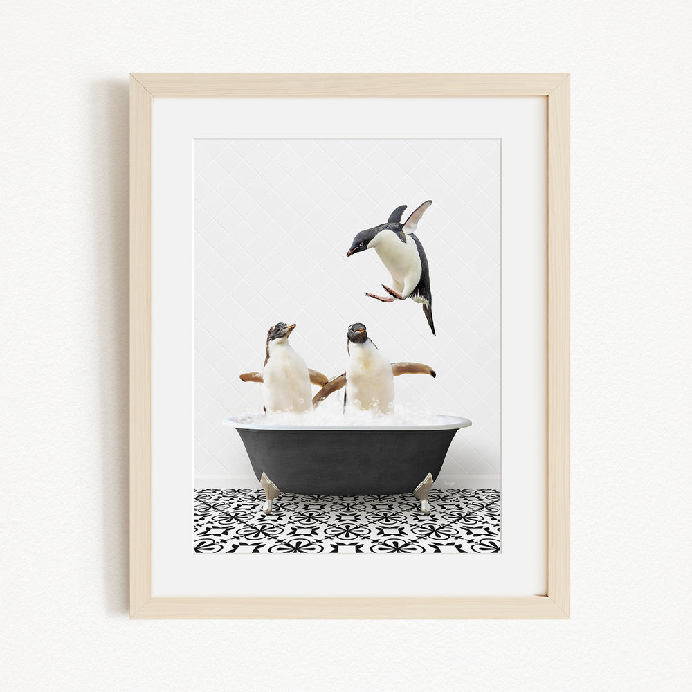 A framed image depicting two penguins sitting in a bathtub, with one penguin flying towards the other.