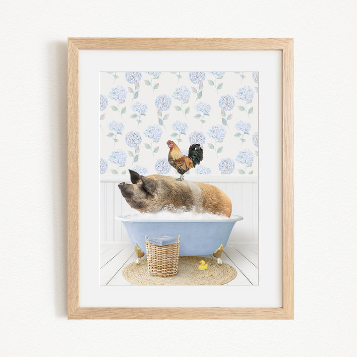 A framed image depicting a pig sitting in a bathtub, with a rooster perched on its back, and a basket of rubber ducks nearby.