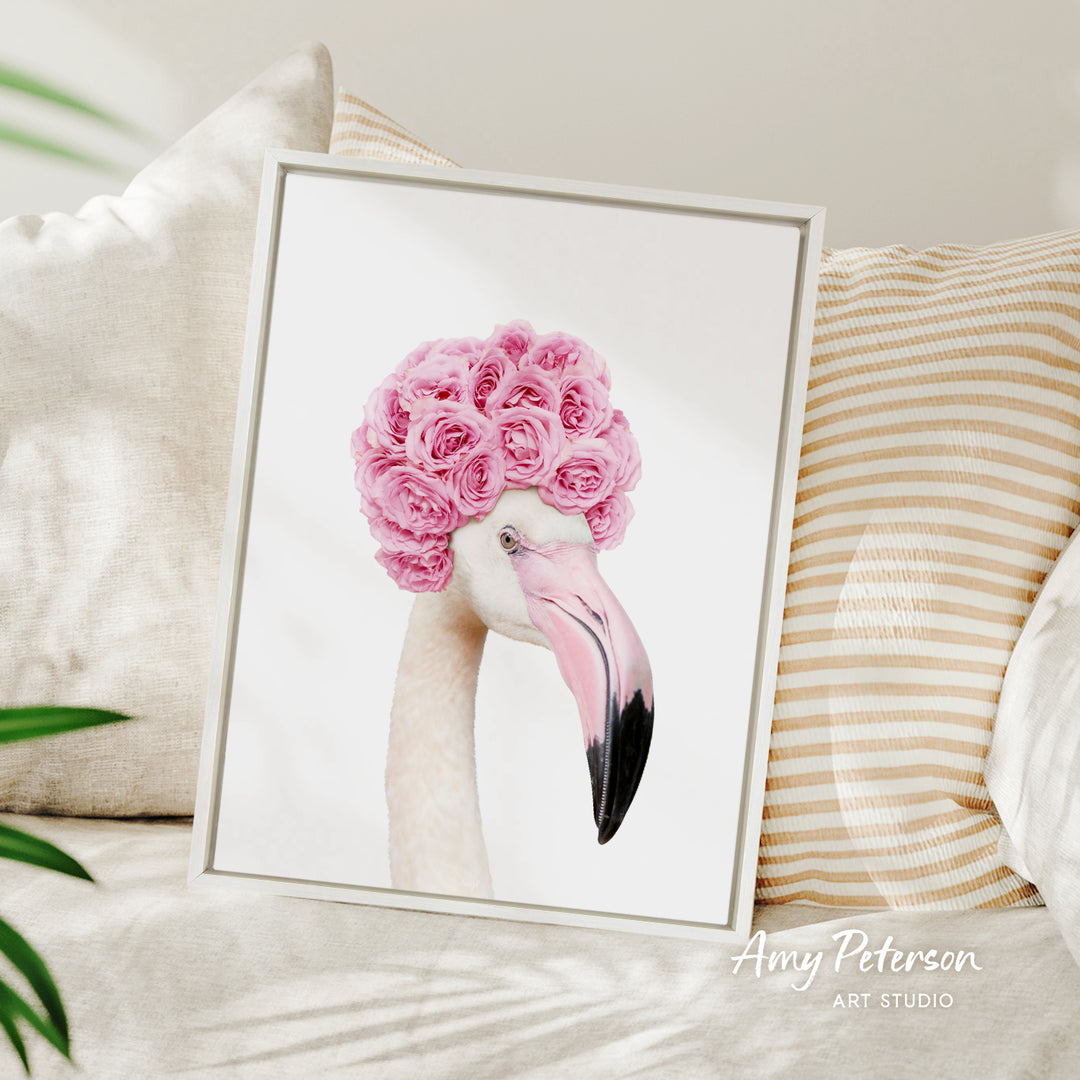 A framed image of a flamingo with pink flowers on its head, displayed on a bed with striped pillows.