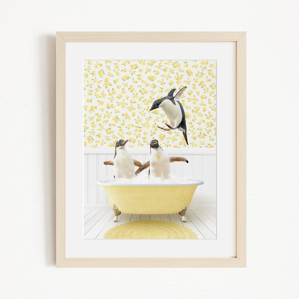 A framed image depicting three penguins sitting in a yellow bathtub, with one penguin standing on the edge of the tub and another penguin sitting inside the tub.
