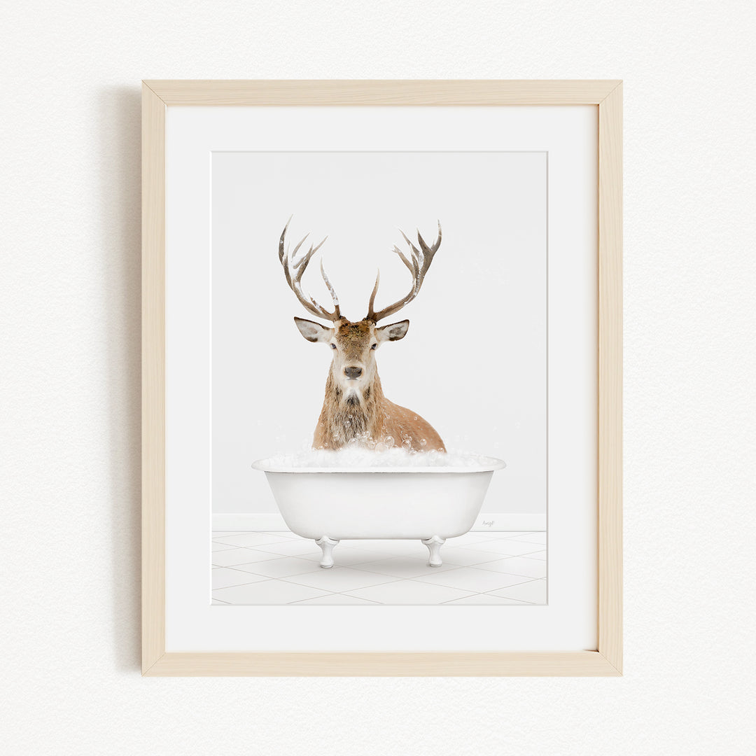 A deer with large antlers is sitting in a white bathtub filled with water, creating a whimsical and unexpected scene.