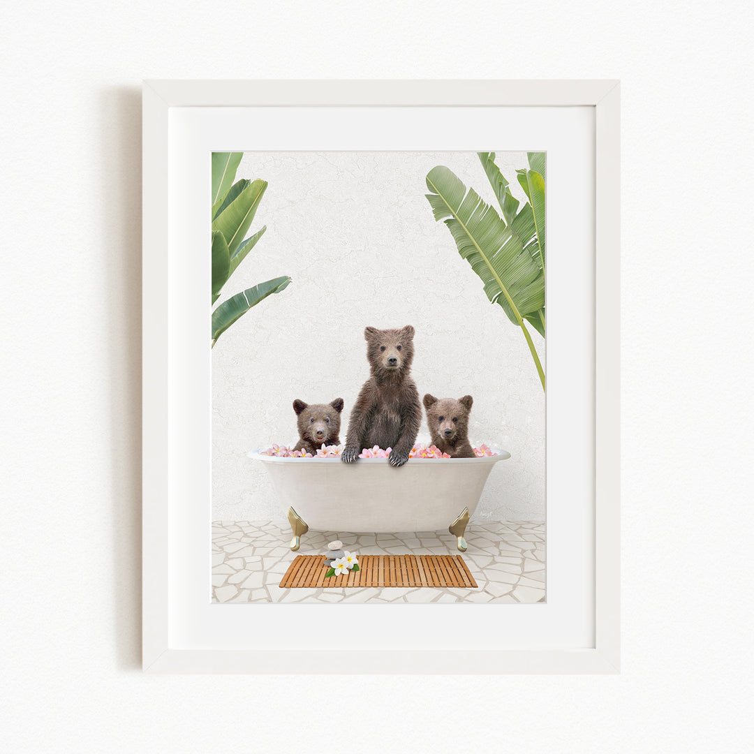 A framed image depicting three bears sitting in a bathtub filled with pink flowers, surrounded by green plants.