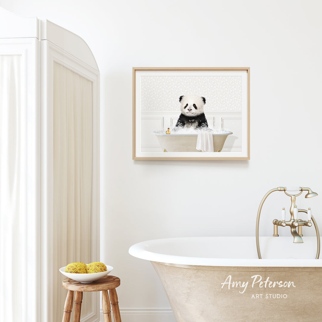 A framed image of a panda sitting in a bathtub is hanging on a white wall above a freestanding bathtub in a bathroom.