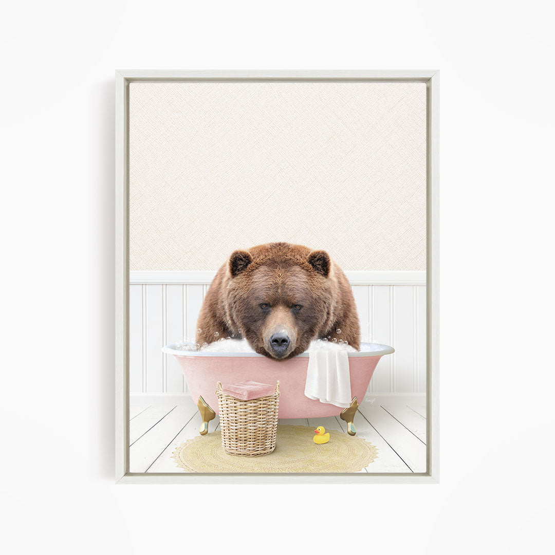 A brown bear is sitting in a pink bathtub filled with water, surrounded by a yellow rubber duck and a white towel.