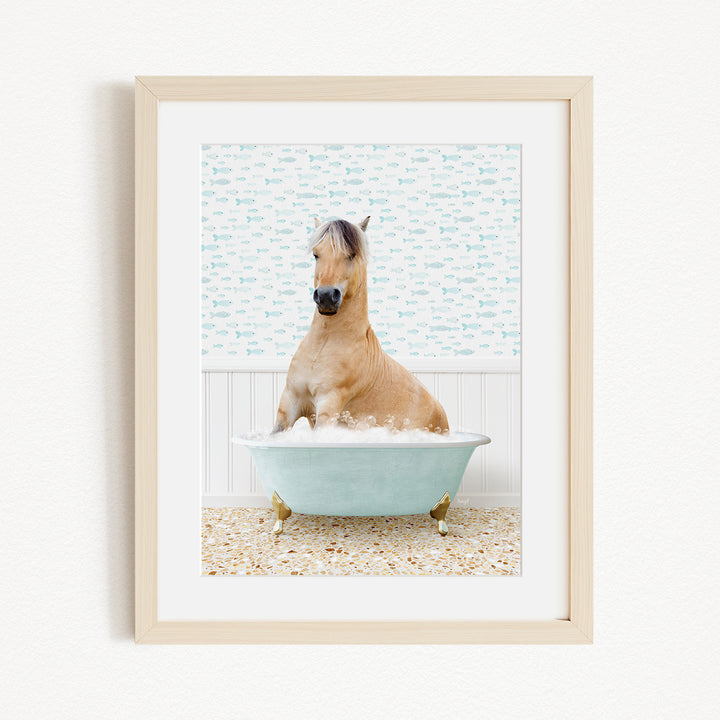 A light brown horse is sitting in a blue bathtub filled with water, surrounded by a patterned wall and a beige floor.