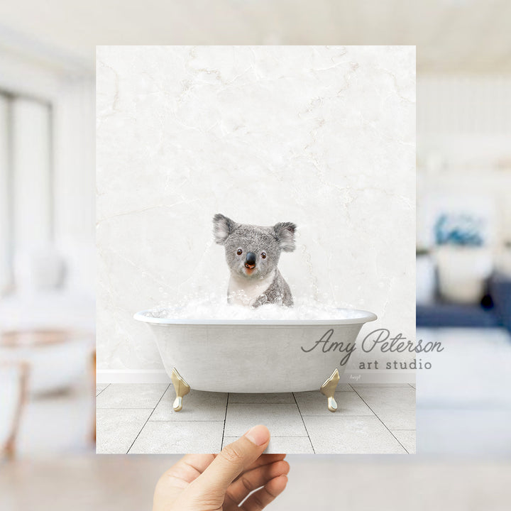 a hand holding a photo of a koala in a bathtub