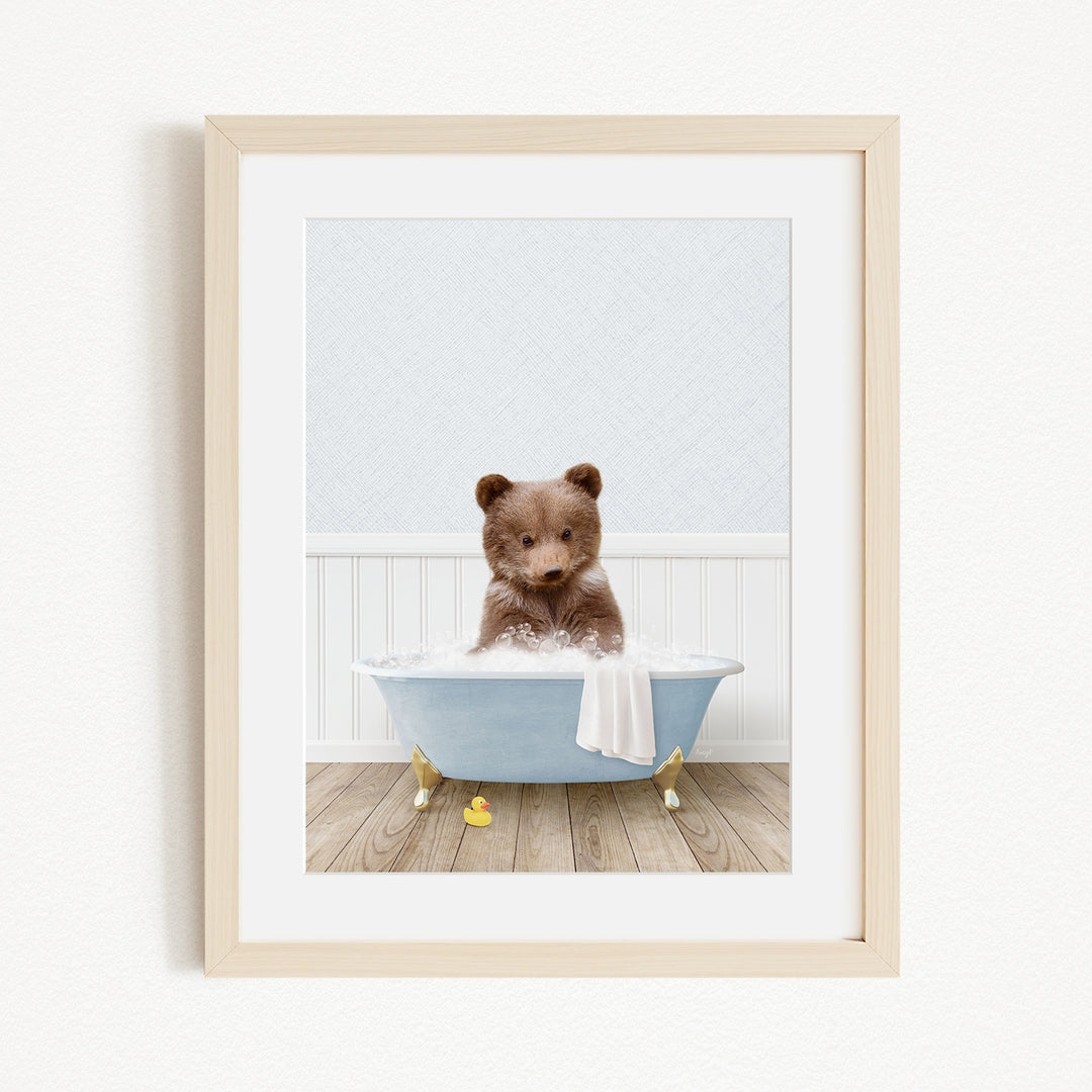 A cute brown bear sitting in a blue bathtub filled with bubbles, surrounded by yellow rubber duckies.