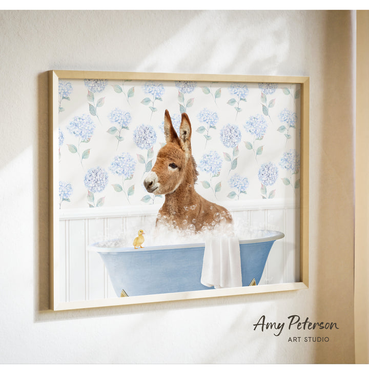 A donkey is sitting in a blue bathtub filled with bubbles, with a yellow duck nearby, against a backdrop of blue hydrangea flowers.