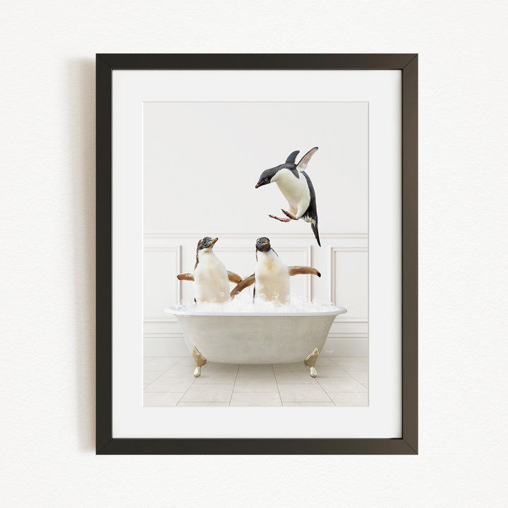 A framed image depicting two penguins sitting in a bathtub, with one penguin flying towards the other penguin.