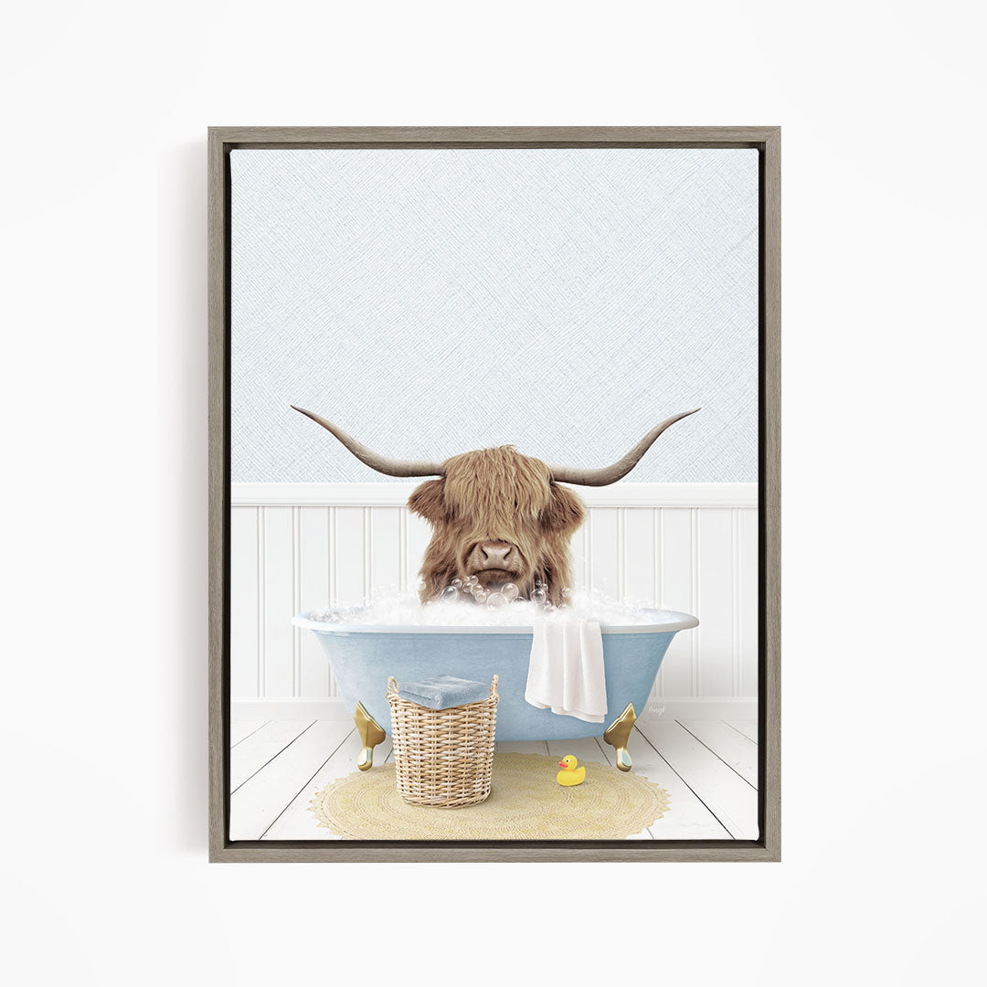 A brown cow with long horns is sitting in a blue bathtub filled with water, surrounded by a yellow rubber duck and a basket.
