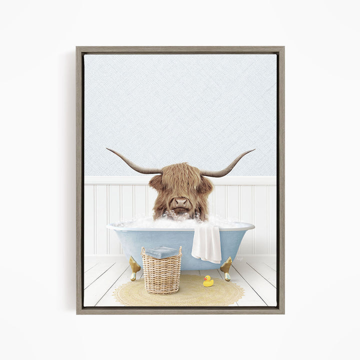 A brown cow with long horns is sitting in a blue bathtub filled with water, surrounded by a yellow rubber duck and a basket.