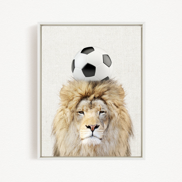 A framed image of a lion with a soccer ball on its head.