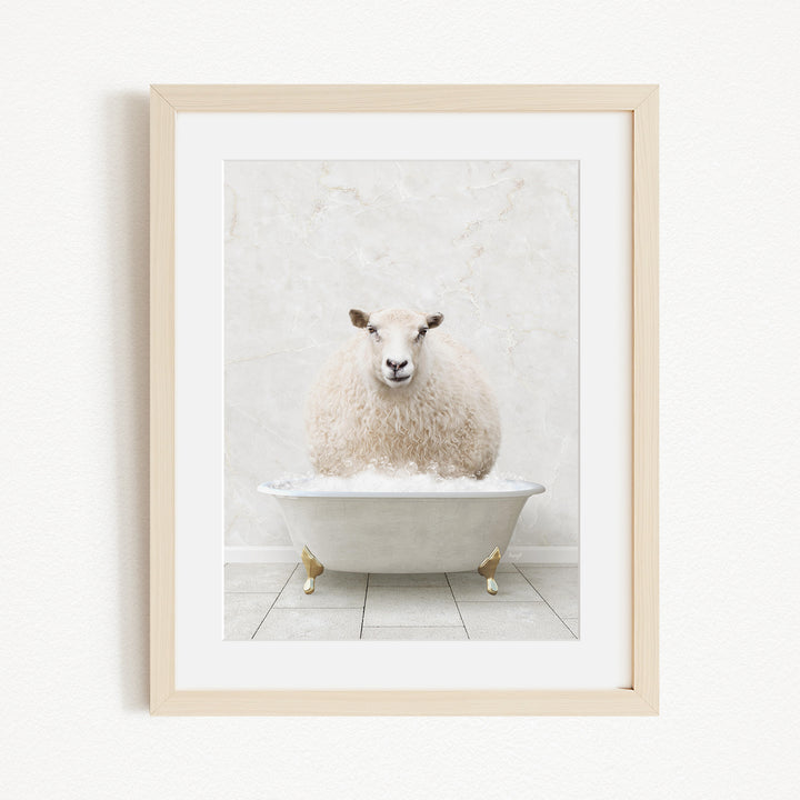 A fluffy white sheep sits in a white bathtub, surrounded by a white marble wall and a wooden floor.