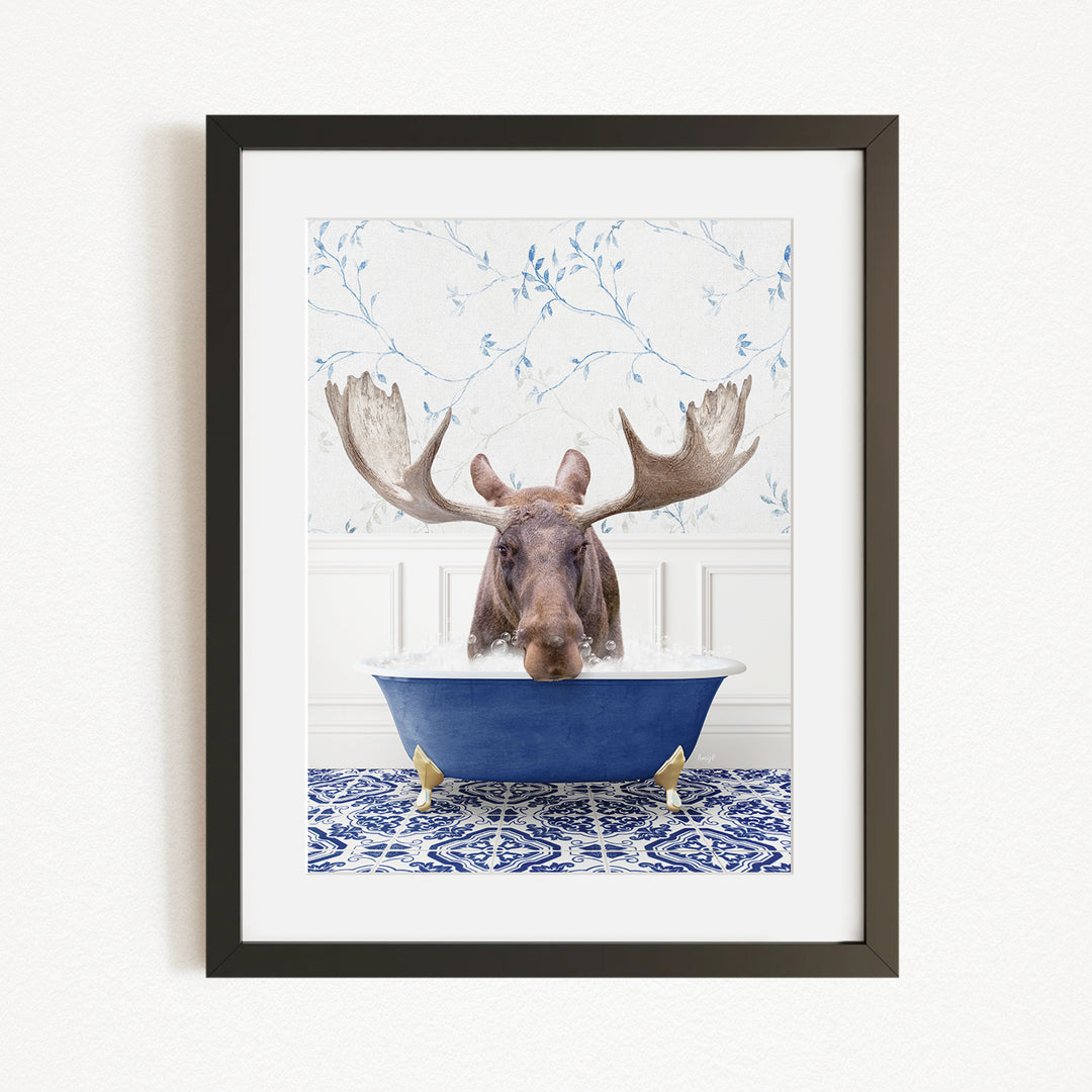 A moose with large antlers is sitting in a blue bathtub, surrounded by a blue and white patterned rug and a white wall with blue floral wallpaper.