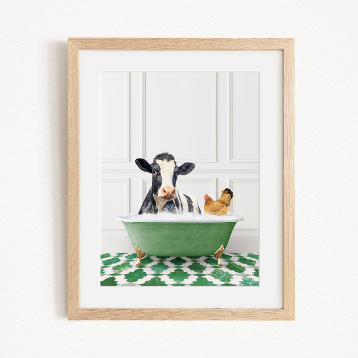 A framed image depicting a cow and a chicken relaxing in a green bathtub, with a patterned green and white rug on the floor.
