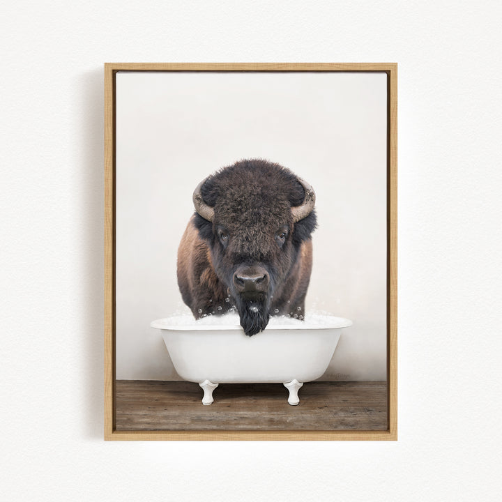 A buffalo with large horns is standing in a white bathtub filled with water, creating a whimsical and humorous scene.