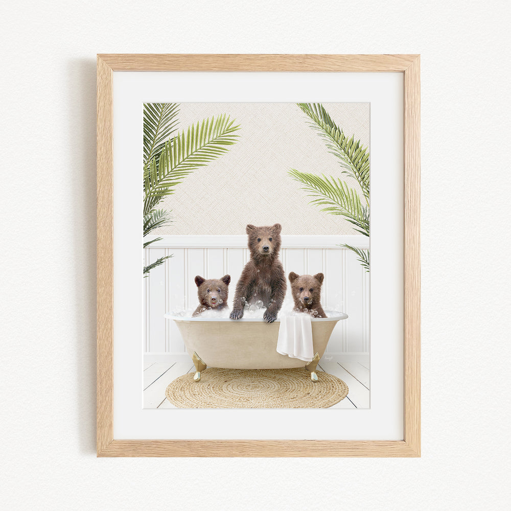 A framed image depicting three brown bears sitting in a bathtub, surrounded by green palm leaves.