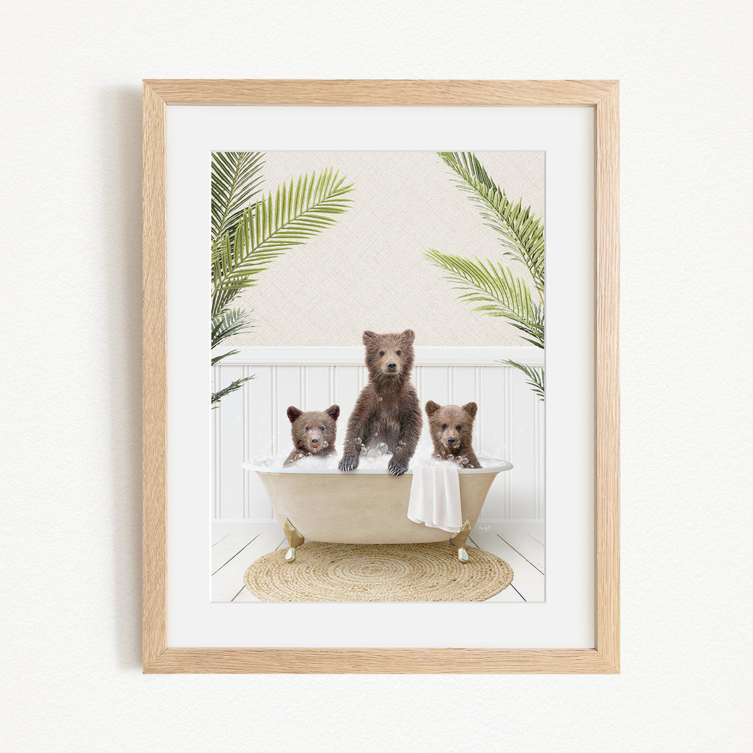 A framed image depicting three brown bears sitting in a bathtub, surrounded by green palm leaves.