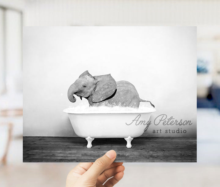 a hand holding up a black and white photo of an elephant in a bathtub