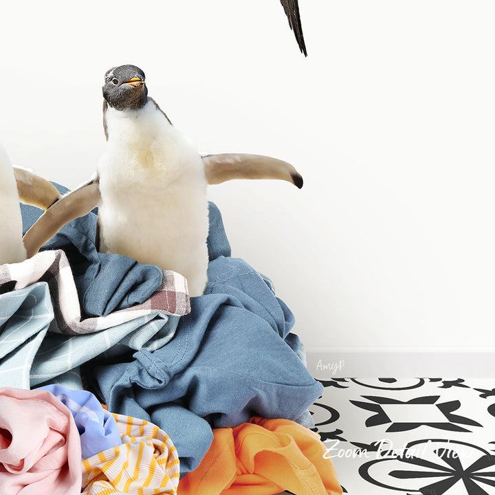 A penguin standing on a pile of clothes, with a black and white patterned floor in the background.