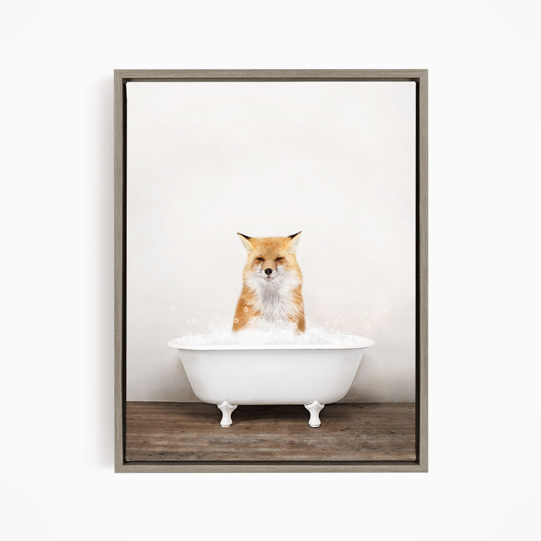 A red fox sitting in a white bathtub filled with bubbles, looking directly at the camera.