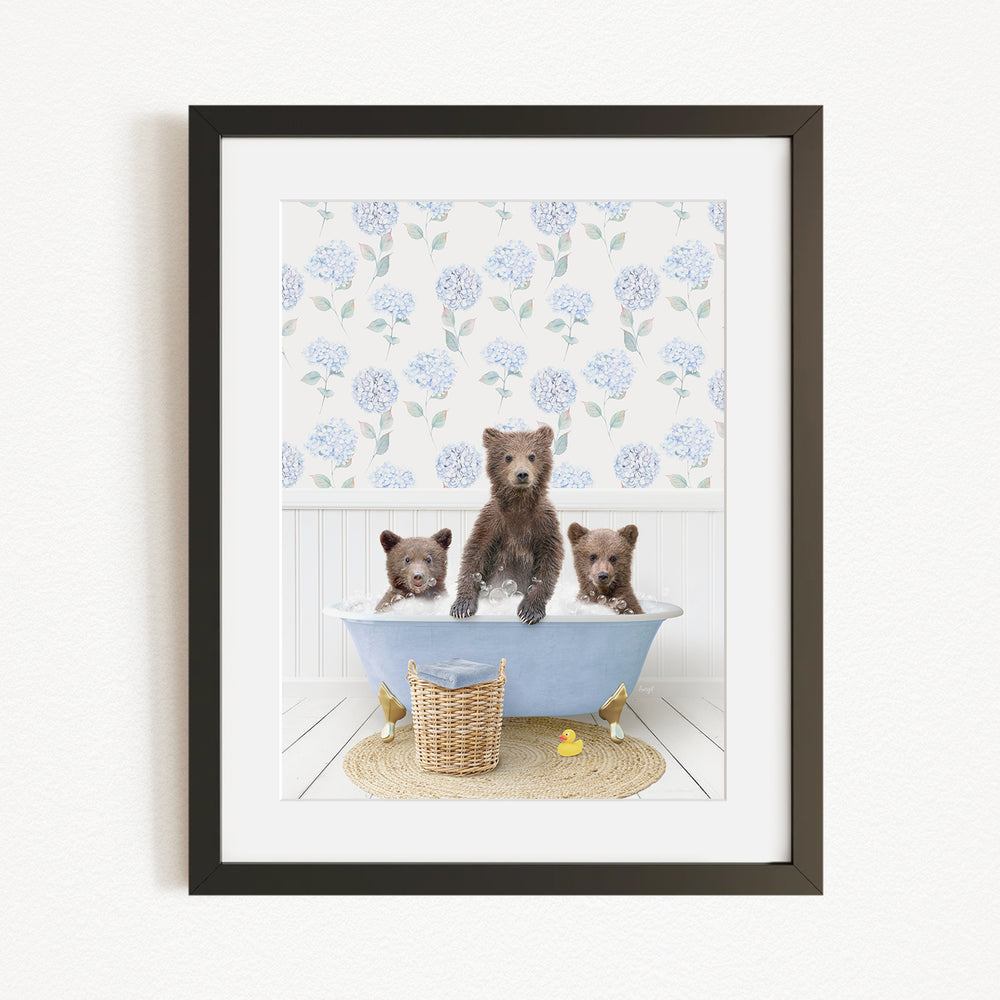 A framed image depicting three bears sitting in a bathtub filled with water, surrounded by a floral patterned wall and a basket of rubber ducks.
