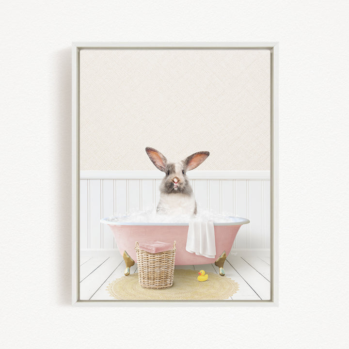 A white rabbit sitting in a pink bathtub filled with bubbles, surrounded by a yellow rubber duck and a wicker basket.