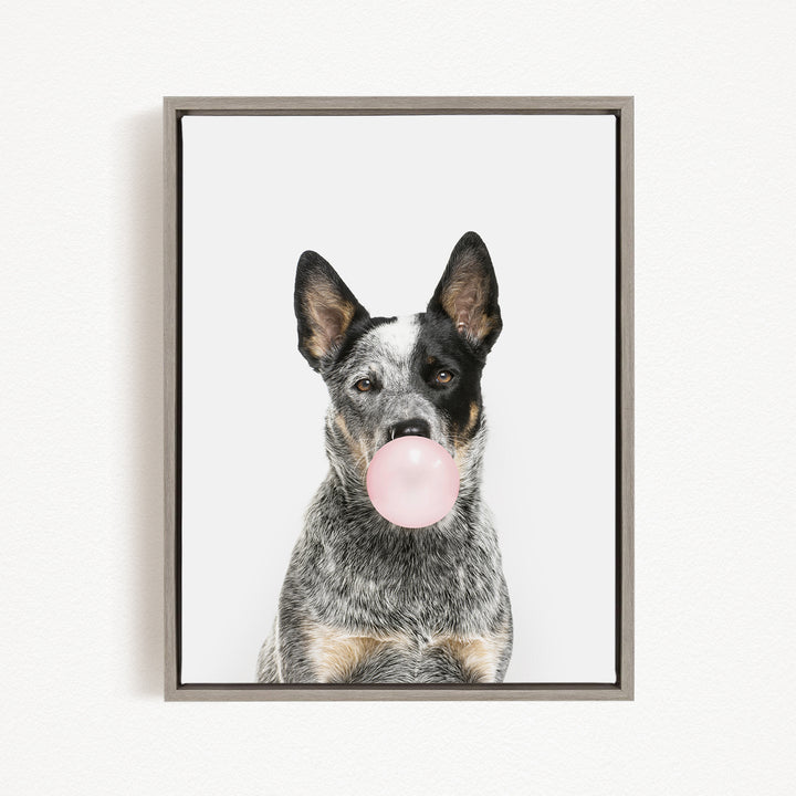 A black and white dog is blowing a pink bubble with its mouth, creating a playful and whimsical scene.