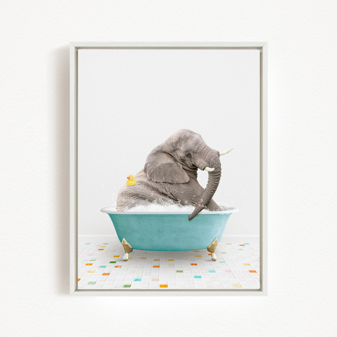 A gray elephant is sitting in a blue bathtub filled with bubbles, with a yellow rubber duck floating nearby.