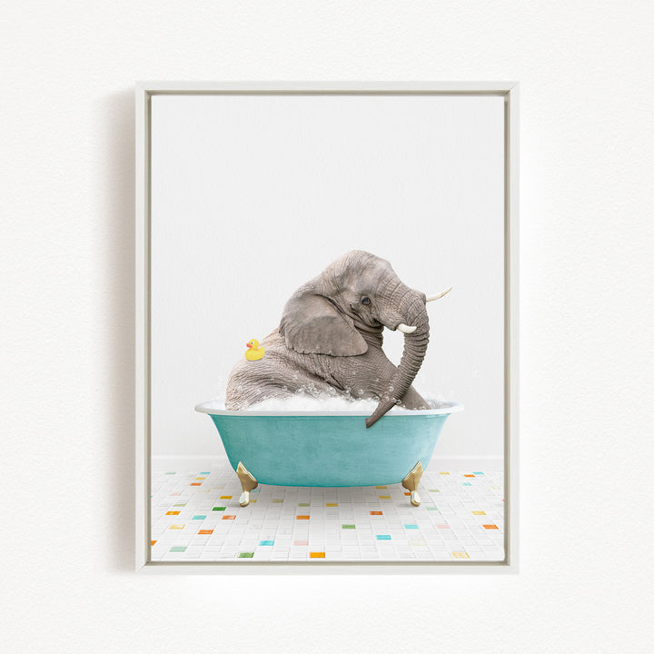 A gray elephant is sitting in a blue bathtub filled with bubbles, with a yellow rubber duck floating nearby.