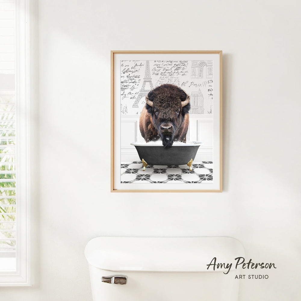 A framed image of a buffalo sitting in a bathtub, with a black and white checkered floor and a window in the background.