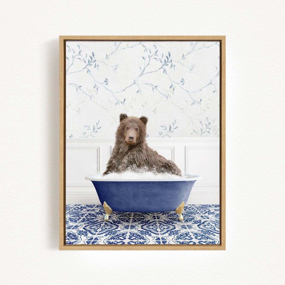 A brown bear sitting in a blue bathtub filled with bubbles, surrounded by a blue and white patterned rug on the floor.