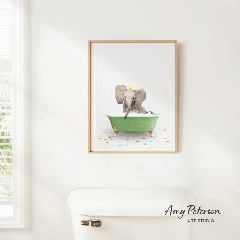 A framed print of an elephant sitting in a green bathtub is hanging on a white wall.