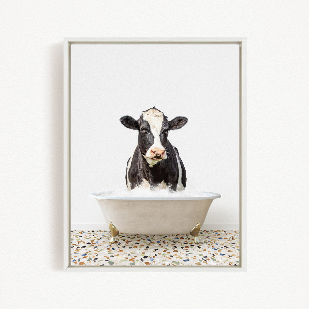 A black and white cow is sitting in a white bathtub filled with water, creating a whimsical and humorous scene.
