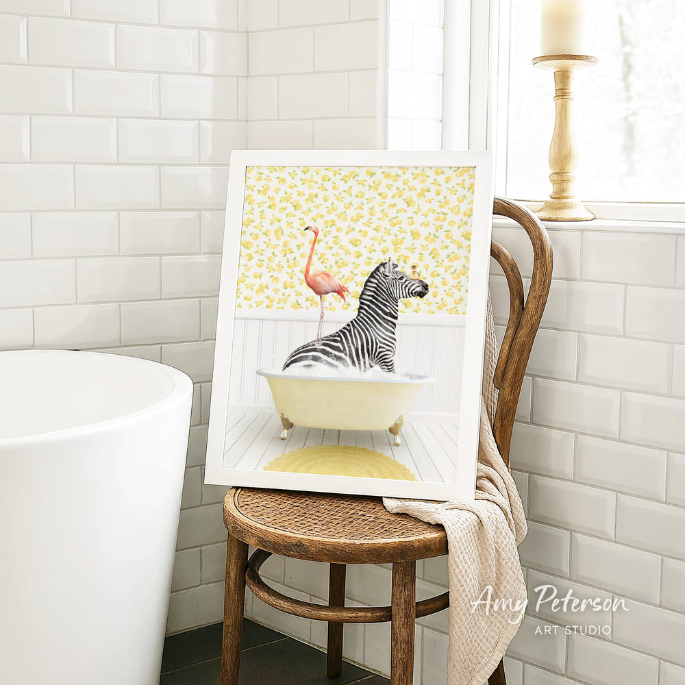 A framed painting of a zebra sitting in a bathtub, with a pink flamingo perched on its back, is displayed on a wooden chair in a bathroom setting.
