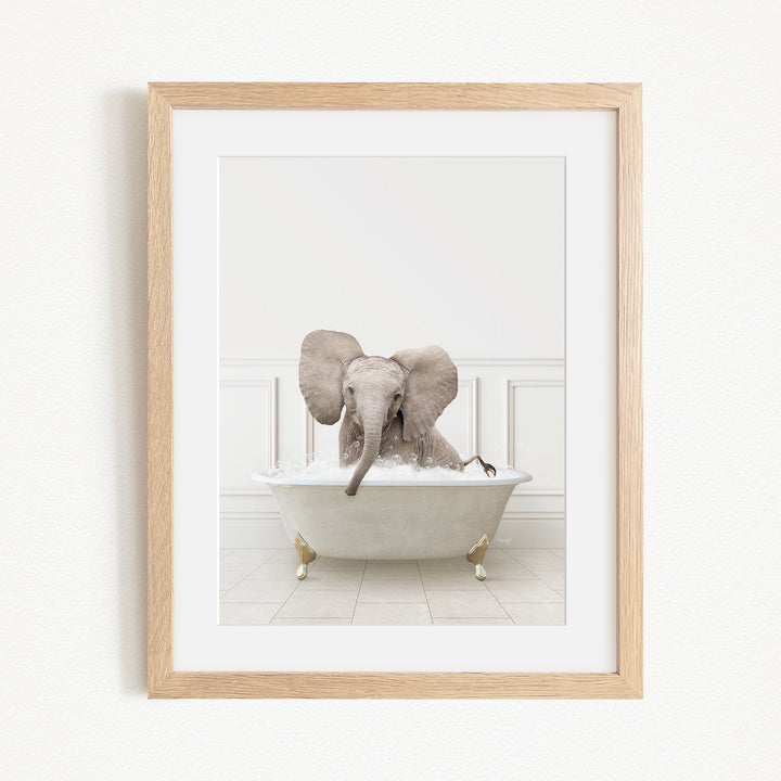 A baby elephant sitting in a white bathtub filled with water, with its trunk submerged in the water.