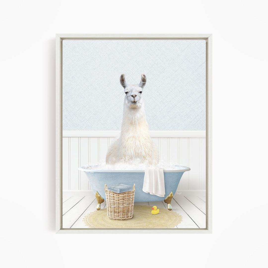 A white llama sitting in a blue bathtub filled with bubbles, surrounded by a yellow rubber duck and a wicker basket.