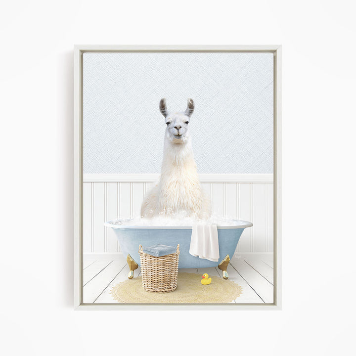 A white llama sitting in a blue bathtub filled with bubbles, surrounded by a yellow rubber duck and a wicker basket.