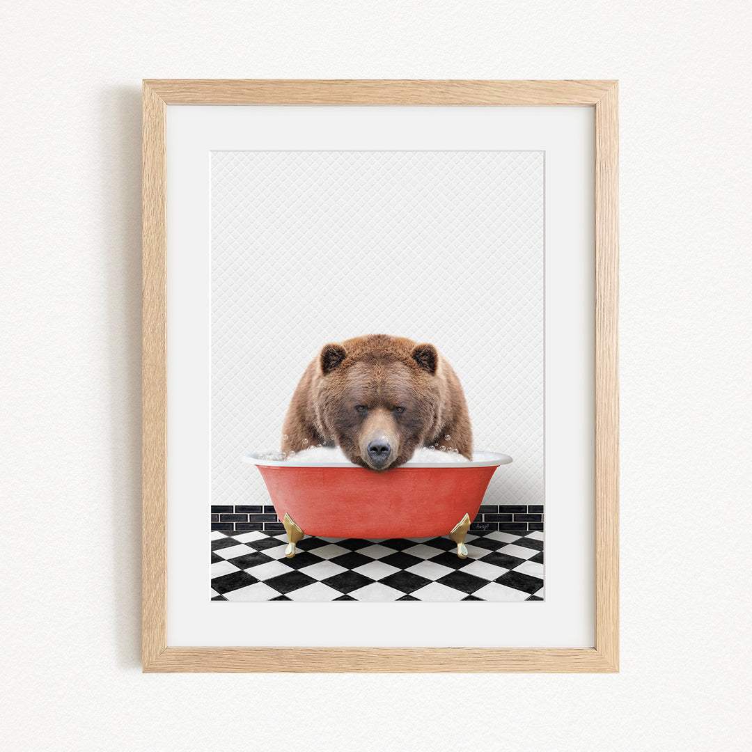 A brown bear is sitting in a red bathtub, appearing to be enjoying a relaxing bath.