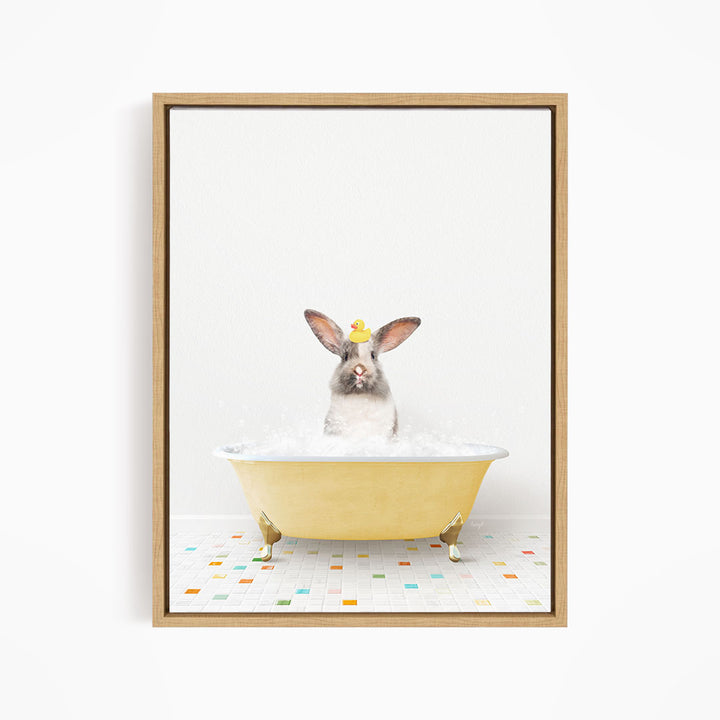 A gray and white rabbit sitting in a yellow bathtub filled with bubbles, wearing a yellow hat.