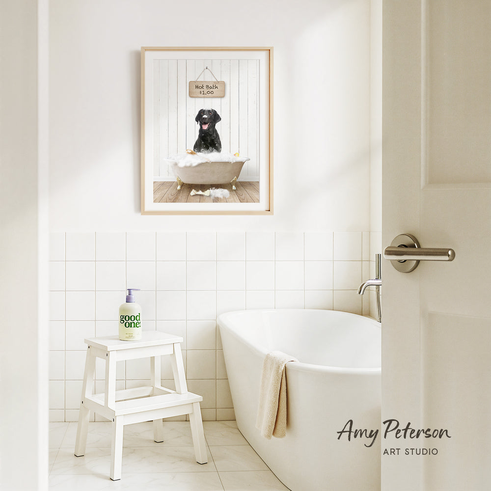 A framed picture of a dog sitting in a bathtub, with a sign above it that says "Hot bath $1.00". The bathroom has a white bathtub, a stool, and a towel hanging on the side of the tub.