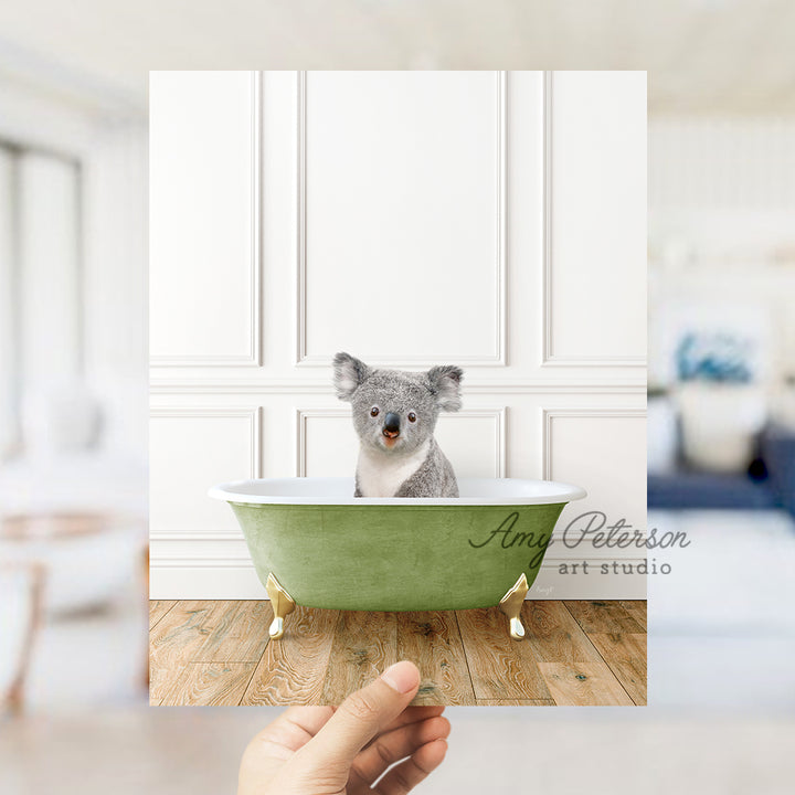 a hand holding a photo of a koala in a bathtub